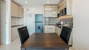 Una cocina moderna con una mesa de madera oscura, armarios de madera clara, una puerta azul y un salpicadero de azulejos.