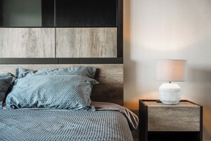 A neatly made bed with patterned bedding, a bedside lamp, and a wooden headboard. - Luxury Babylon Sky Pool & Ocean View C189 (Tambon Rawai)