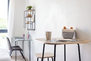 Ein modernes Zimmer mit einem kleinen Tisch, einem Stuhl, einem Bücherregal und einem Fenster.