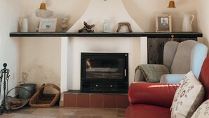 Ein Wohnzimmer mit Kamin, einem roten Sofa und Dekorationen auf Regalen.