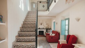 Eine Treppe mit gemusterten Fliesen, ein roter Sessel, ein weißer Tisch und eine blaue Tür.