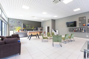 A modern interior with a reception desk, seating area, and a television. - 205 - L'Obsidienne - Wifi (Achères)