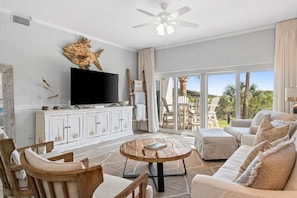 A spacious living room with a large TV, wooden furniture, and a view of the outdoors. - Coastal Retreat at TOPSL - Sleeps 6 (Miramar Beach)