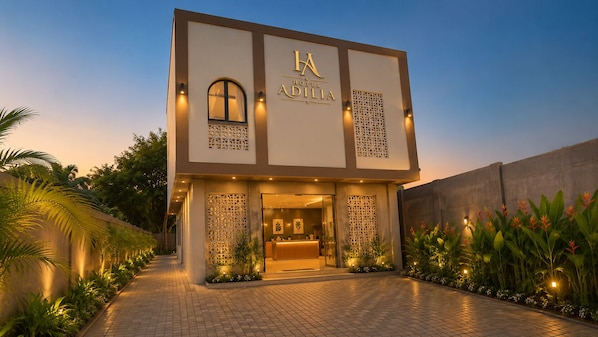 A modern hotel entrance with a reception desk, decorative lattice panels, and a well-lit pathway. - Adilia Hotel (Labuan Bajo)