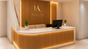 Uma receção de hotel com design moderno, um logotipo acima do balcão e um monitor de computador.
