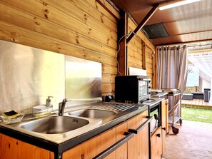 A wooden cabin with a kitchen featuring a double sink, a stove, and a microwave. - Joli Cœur - Jacuzzi - Terrasse - Jardin (Saint-Louis)