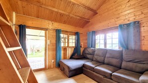 Un interior de madera con sofá, cortinas y una ventana.