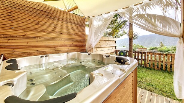 Un jacuzzi con terraza de madera y vistas a las montañas.