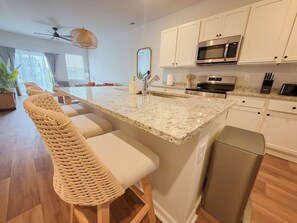 A modern kitchen with white cabinets, a granite countertop, a stainless steel oven, and a built-in microwave. - Spacious 3BR Home with Water Views, Pool Access & Family Amenities (Myrtle Beach)