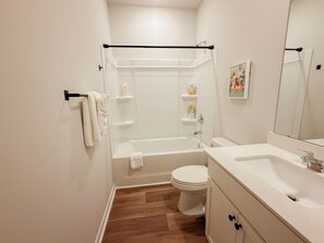Et badeværelse med badekar, toilet og vaskebord med spejl.
