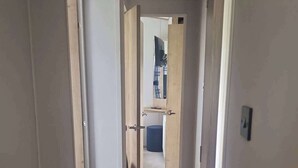 A corridor with open doors leading to a room with a bed and a desk. - 3 Bed - Sleeps 8 - Family & Pet Friendly (Skegness)