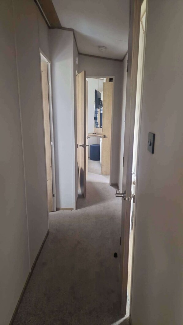 A corridor with open doors leading to a room with a bed and a desk. - 3 Bed - Sleeps 8 - Family & Pet Friendly (Skegness)