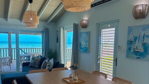 Un'ampia zona giorno con un tavolo da pranzo in legno, un piano cottura integrato e vista sull'oceano attraverso ampie finestre.