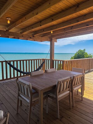 A wooden deck with a table and chairs, overlooking a body of water.