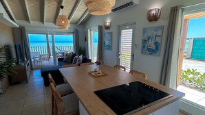 Un'ampia cucina con un'isola grande, soffitto in legno e vista mare.