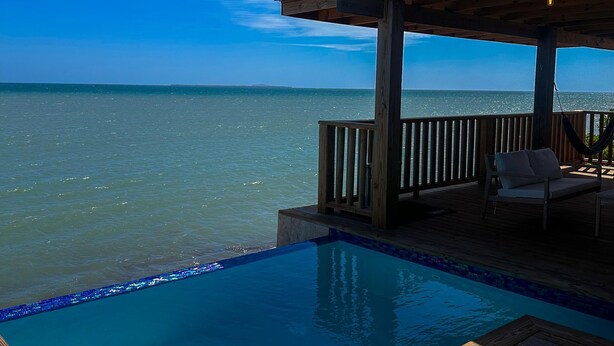 Un patio in legno con piscina che si affaccia sull'oceano.