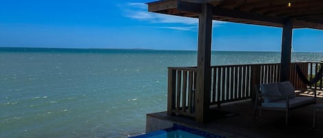 A wooden deck with a pool overlooking the ocean.