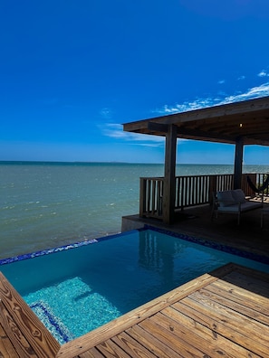 A wooden deck with a pool overlooking the ocean.