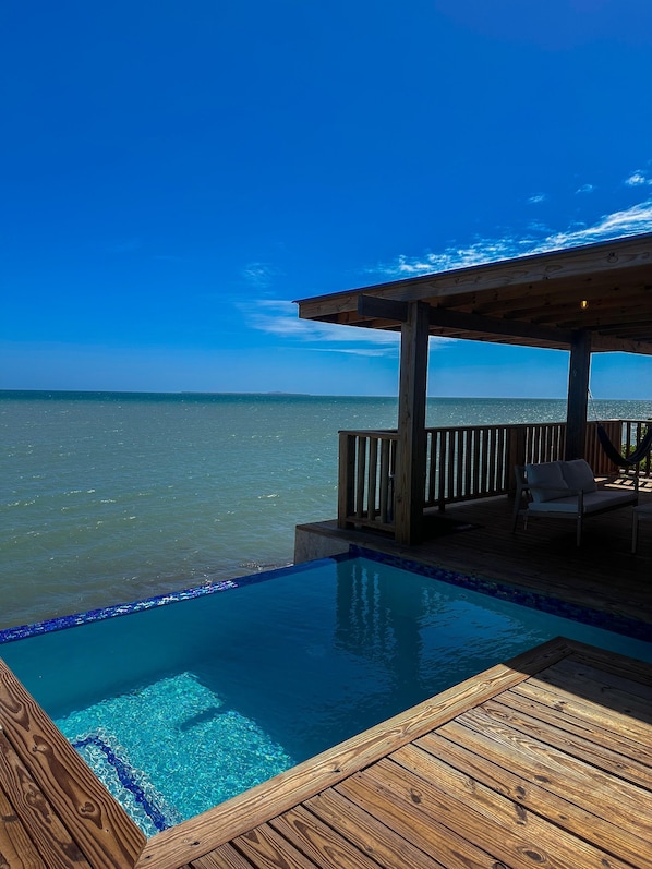 A wooden deck with a pool overlooking the ocean.