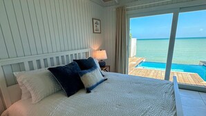 Una camera da letto con un letto, un comodino, una lampada e vista sull'oceano.