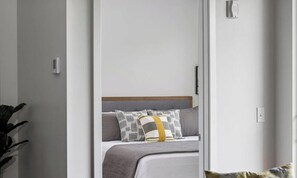 Ein Schlafzimmer mit einem Bett, Kissen, einem Nachttisch und einer Wandleuchte.