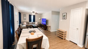 A living room with a sofa, TV, dining table, and chairs. - Private Pool, Near NRG Stadium & Texas Medical & Downtown (Houston)