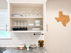 Een keuken met witte kastjes, een decoratie met Texaanse thema, en een granieten aanrecht met koffiezetapparaat, waterkoker en een klein plantje.