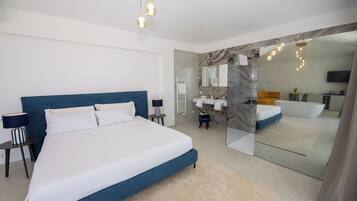 Un dormitorio moderno con una cama grande, mesitas de noche, un espejo y un baño con bañera y lavamanos.