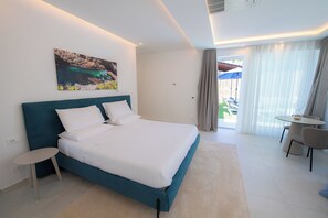Una habitación de hotel moderna con cama, una mesita, una silla, un cuadro en la pared y vistas al exterior.