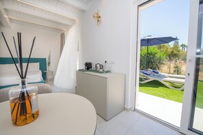 Una camera da letto moderna con un letto, un comodino, una piccola credenza e vista su un patio esterno con tavolo e sedie.