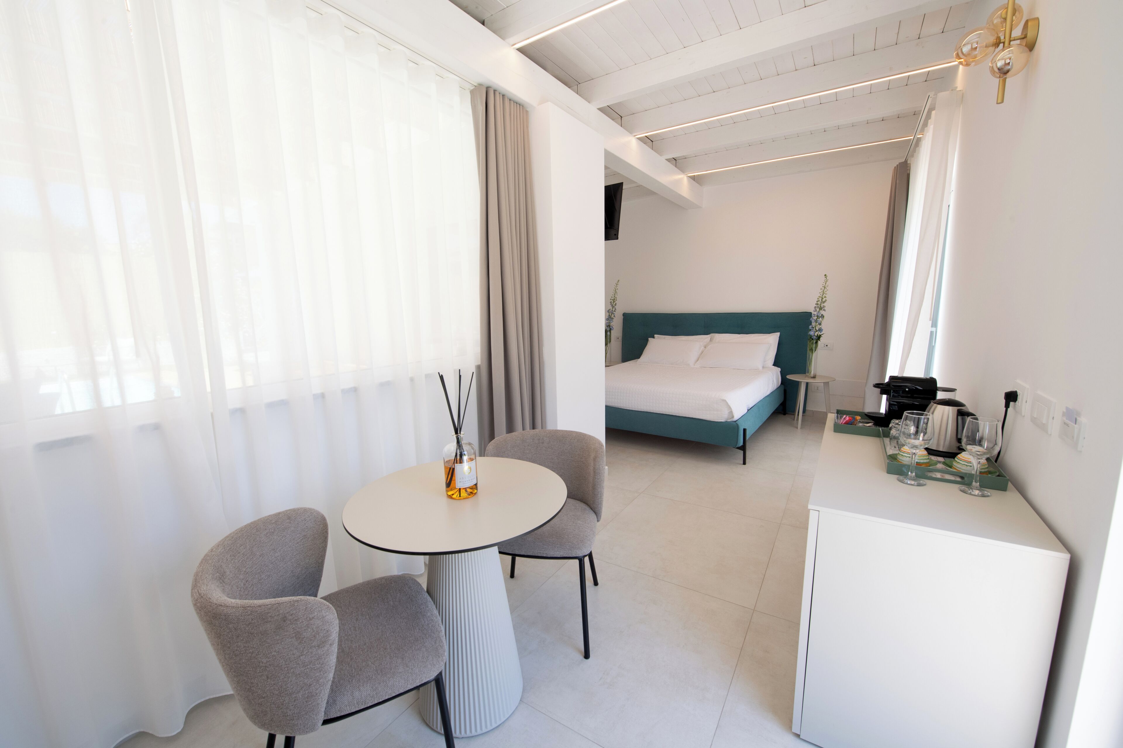 Een hotelkamer met een bed, een tafeltje met stoelen en een minibar.