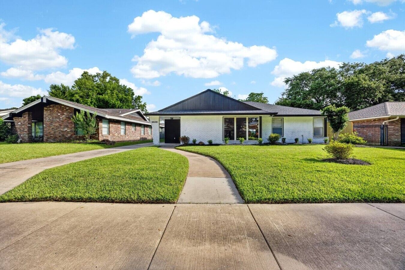 A residential house with a front yard, driveway, and a clear sky.