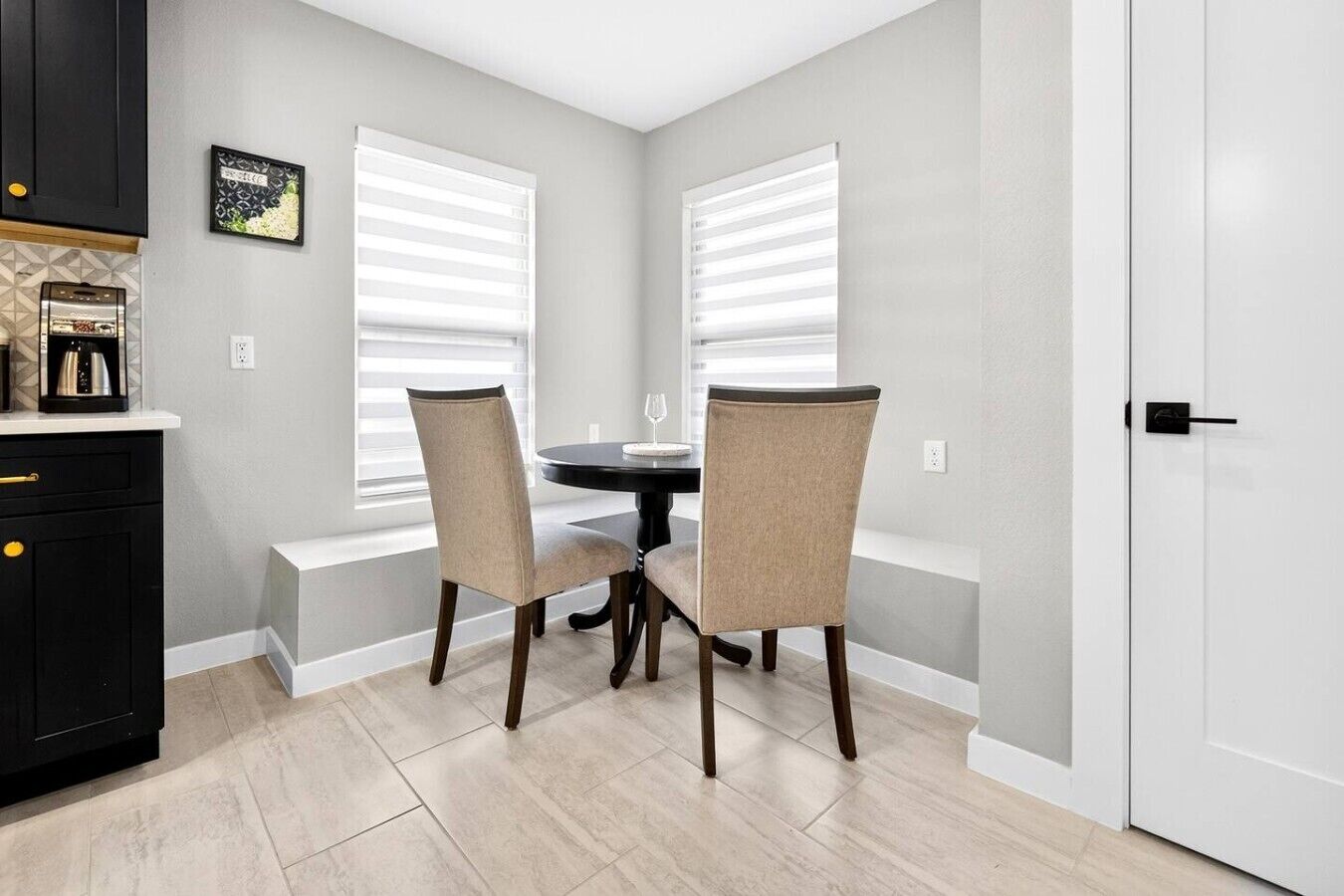 A dining area with two chairs, a table, and a kitchen counter with appliances.