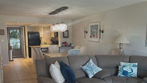 Uma sala de estar com sofá, mesa de centro e área de jantar com cadeiras.