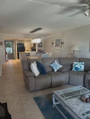 A living room with a sofa, a coffee table, and a dining area with chairs. - Beautiful 2-bedroom, 2-bathroom condo in charming St. Augustine Beach. (St. Augustine)