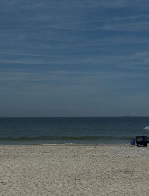 Ein Strand mit blauem Himmel, ruhiger See und einigen Liegestühlen.