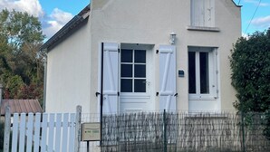 Una casa de una planta con techo a dos aguas, paredes exteriores blancas y un pequeño porche delantero.