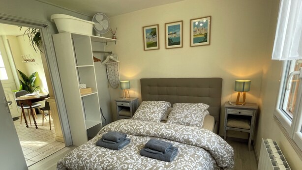 Un dormitorio con cama, mesitas de noche, un escritorio y una silla. Hay tres cuadros enmarcados en la pared.