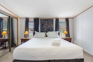 A hotel room with a large bed, two bedside tables with lamps, a mirror, and a view of the outdoors. - 1BR aviation retreat w/ pool & backyard (Clermont)