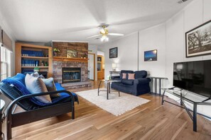 A living room with a fireplace, a sofa, a coffee table, and a TV. - 1BR aviation retreat w/ pool & backyard (Clermont)