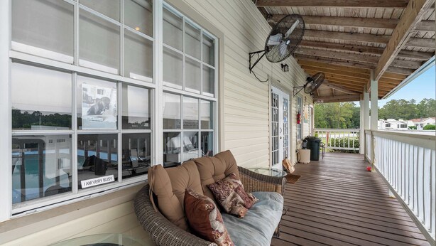 A covered porch with a wicker sofa, two wall fans, and a glass table. - Cozy retreat w/ pool & backyard (Clermont)