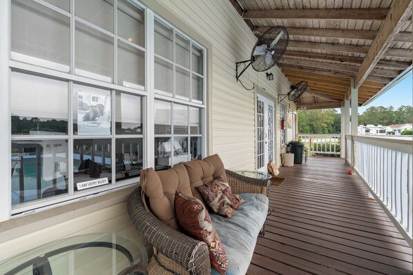 A covered porch with a wicker sofa, two wall fans, and a glass table. - Cozy retreat w/ pool & backyard (Clermont)