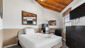 A bedroom with a bed, a dresser, a television, a microwave, and a small table with a plant. - Cozy retreat w/ pool & backyard (Clermont)