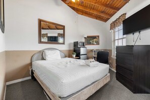 A bedroom with a bed, a dresser, a television, a microwave, and a small table with a plant. - Cozy retreat w/ pool & backyard (Clermont)