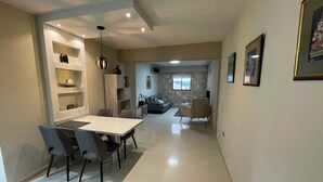 Una sala de estar moderna con comedor, pared de piedra y vistas a través de una ventana.