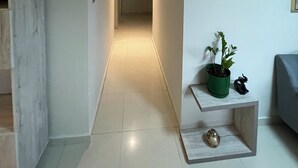Un pasillo con una lámpara, una planta en maceta y un estante con objetos decorativos.