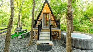 A cabin with a wooden deck, a hot tub, and a picnic table.