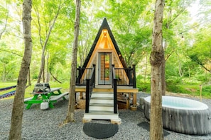 A cabin with a wooden deck, a hot tub, and a picnic table.