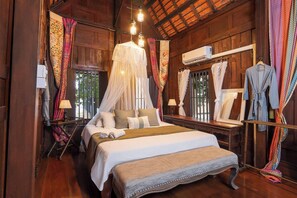 Quarto de madeira com cama, luminária pendente, ar condicionado e espelho.