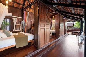 Una habitación de madera tradicional con cama, un banco y vista a un jardín.